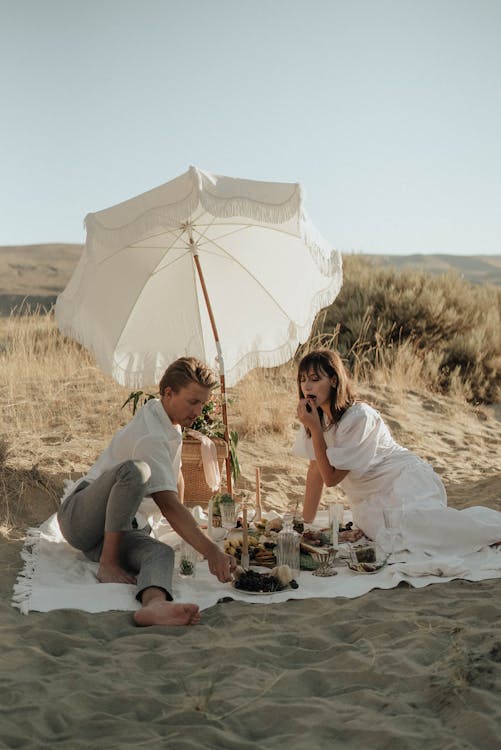 Young couple having picnic on sandy terrain