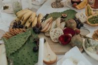 From above of fresh fruit with snacks green opuntia and bread on white cloth for picnic