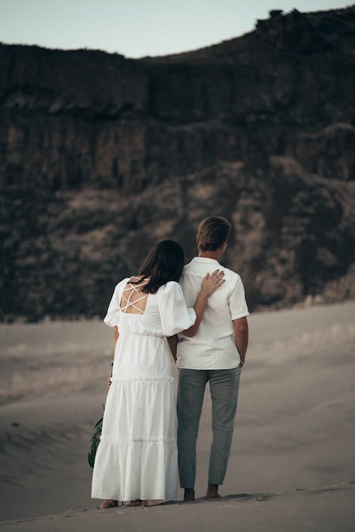 Unrecognizable newlywed couple on sandy terrain