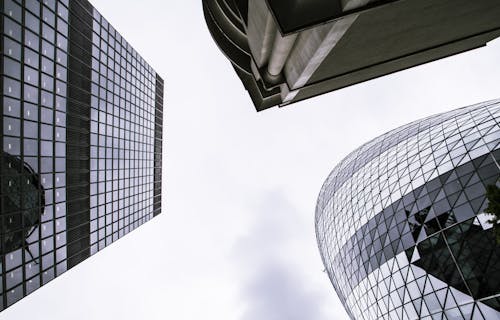 Worm's Eye View of Mirror Covered Concrete Buildings Under Gray Cloudy Skies