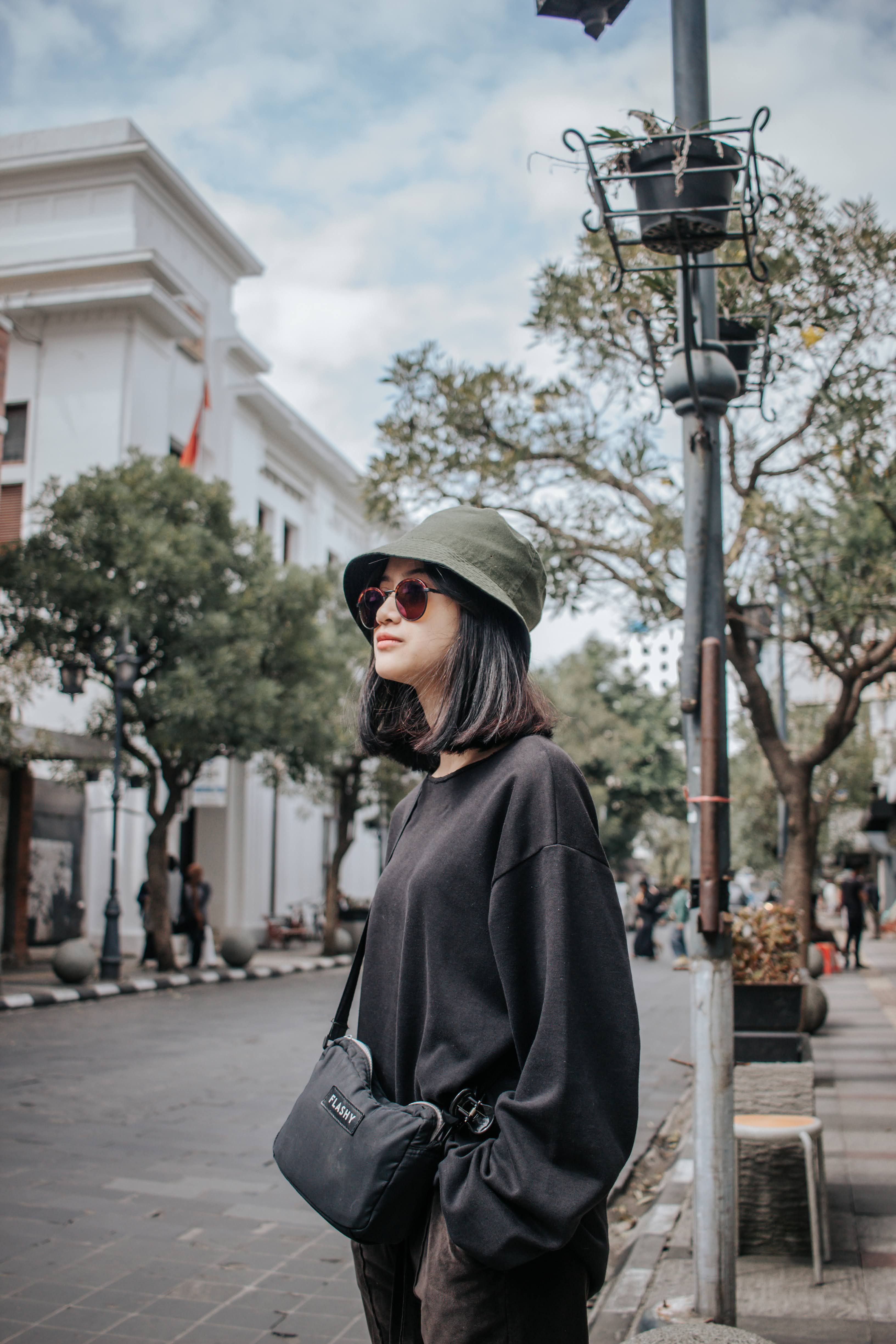 Fashionable woman wearing hat and sunglasses on Bandung street, Indonesia.