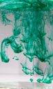 Transparent glass with colorful pigment fluids diffusing fast in pure water on light background