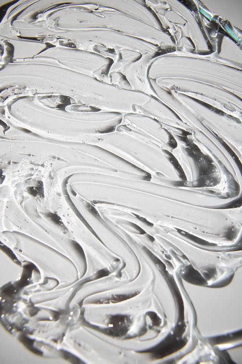 From above of backdrop representing shiny curved gel flows with irregular surface on gray background