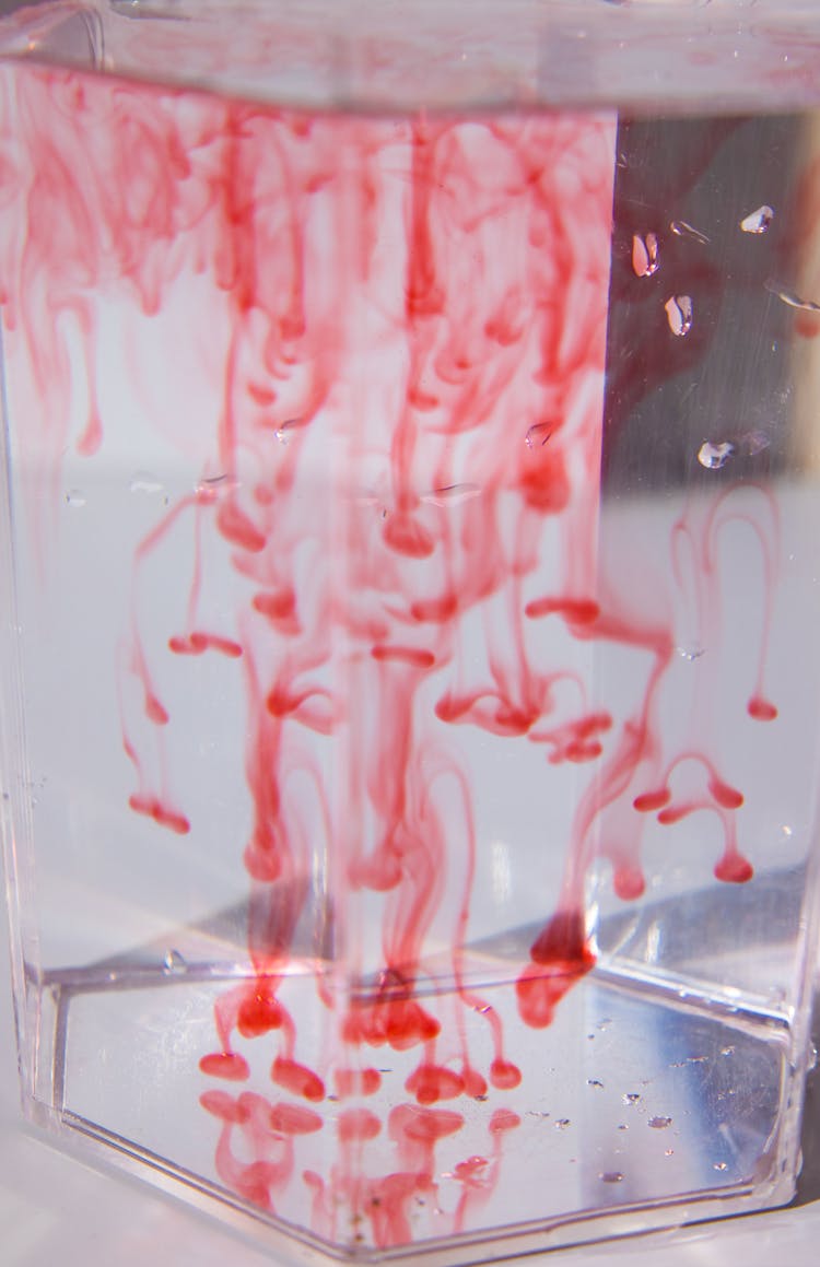 Glass With Red Paint Flows In Water