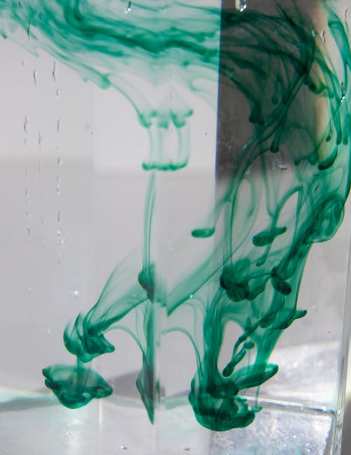 Glass with green paint streams in aqua