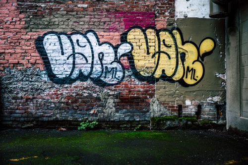 Free Exterior of aged shabby building with brick wall with graffiti inscription on city street Stock Photo
