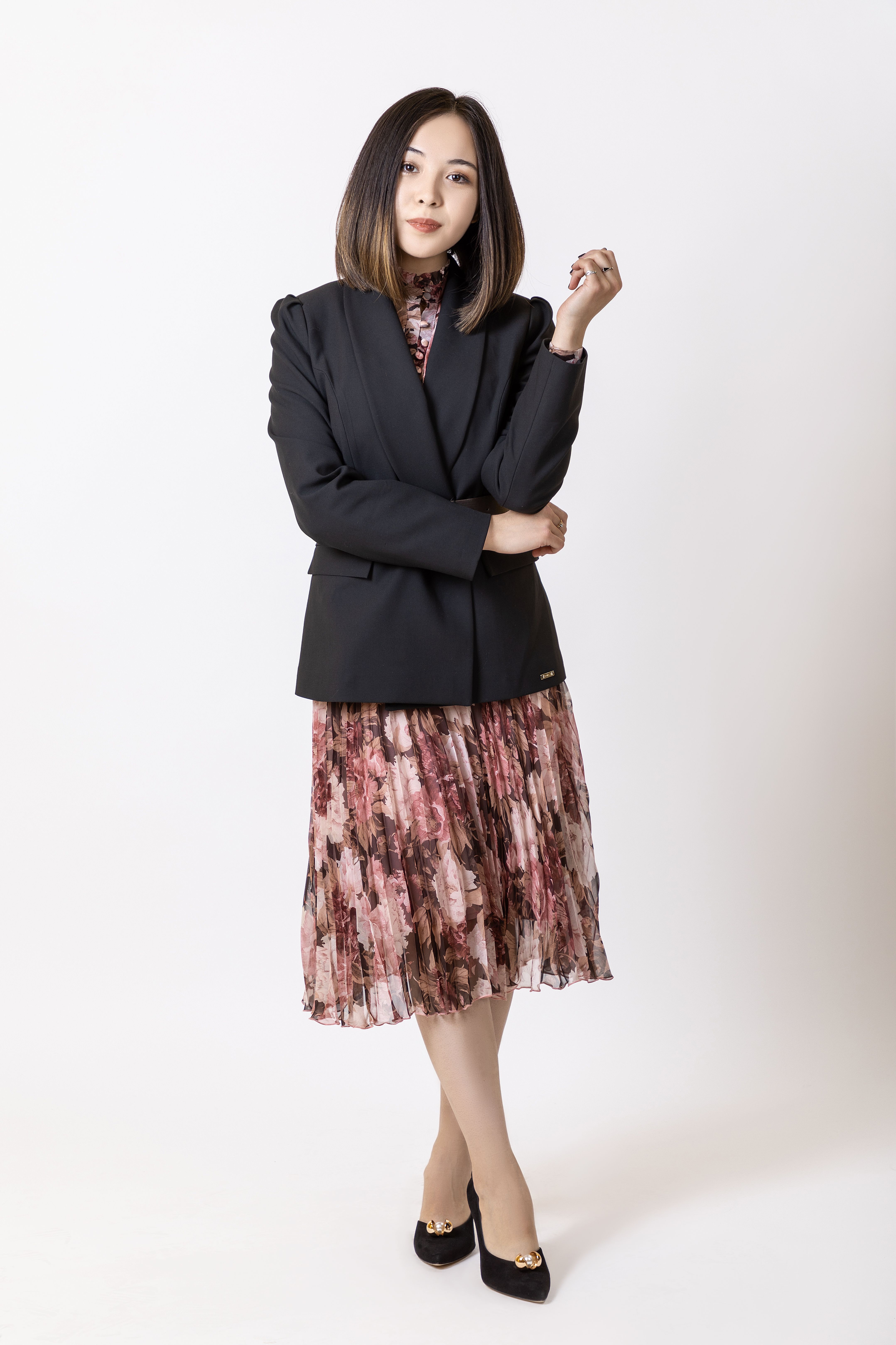 Stylish portrait of a woman in a blazer and floral dress, showcasing fashion and elegance.