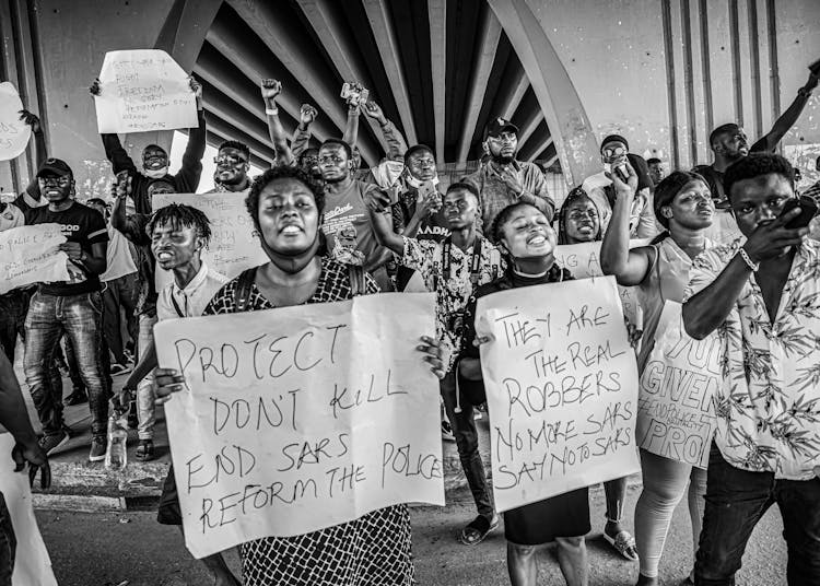 People Holding Banners While Protesting On The Street