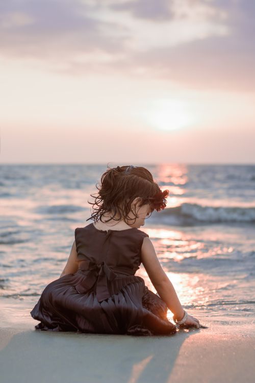 Girl in Brown Dress Sitting on Seashore During Sunset Free Stock Photo Girl in Brown Dress Sitting on Seashore During Sunset Free Stock Photo