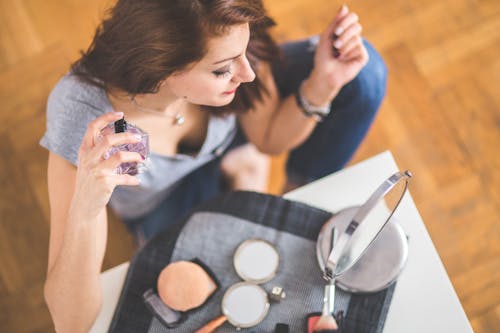 Closeup of a young woman applying perfume