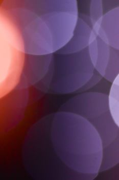 Abstract bokeh background with overlapping light circles in purple and orange hues.