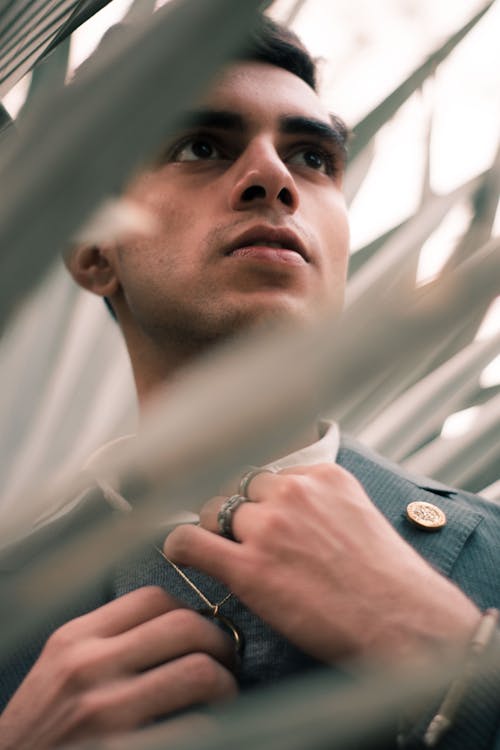 A Man Touching the Silver Necklace he is Wearing while Looking Afar