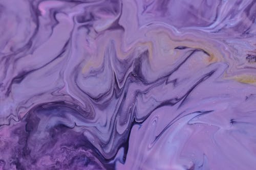Full frame background of glossy purple ink mixing and blending on uneven surface