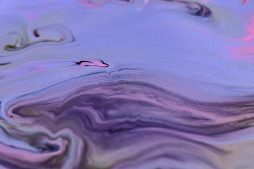 Free Full frame abstract background of diffusing purple ink blending and flowing together on uneven surface Stock Photo