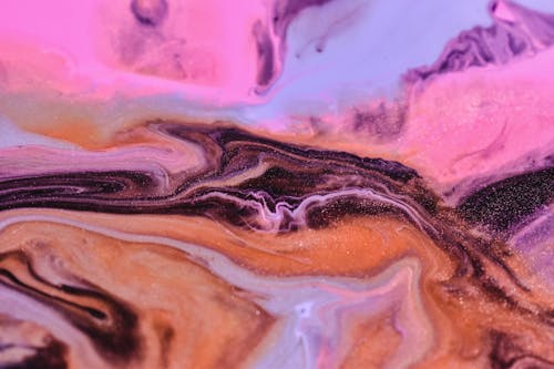 Full frame background of bright blue pink and brown fluids blending together on uneven surface in studio