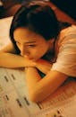 Lonely Asian woman leaning on menu in cafe