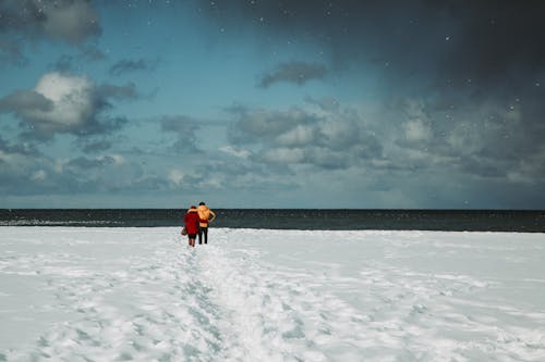 Traveling couple standing on snowy seashore