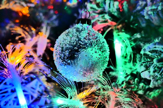 A festive Christmas bauble surrounded by colorful illuminated lights on a decorated tree.
