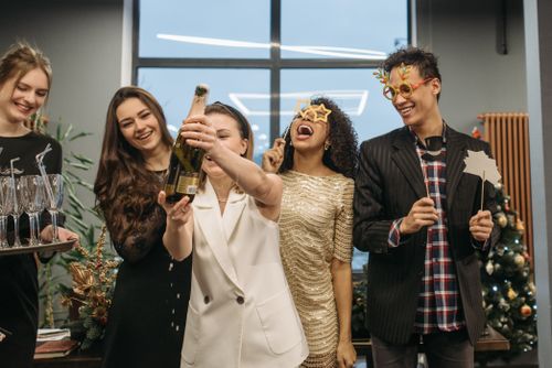 Free Group of colleagues celebrating a festive occasion with champagne and laughter indoors. Stock Photo