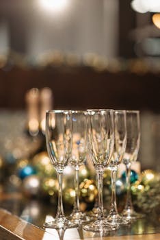 Elegant champagne glasses set for a festive New Year celebration with a blurred background of decorations.