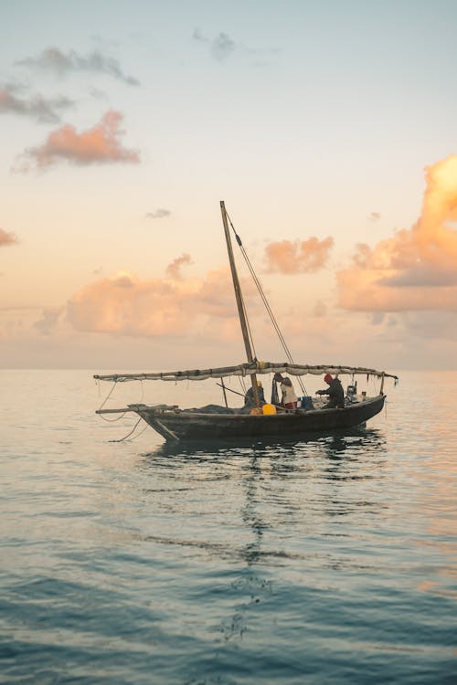 A Fishing Boat On Water With People At Early Sunrise
