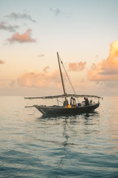 Fishermen on a boat at sunrise, casting nets over a calm ocean backdrop.