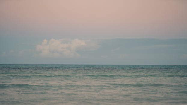 Tranquil ocean view with pastel sunset sky, perfect for travel and relaxation themes.