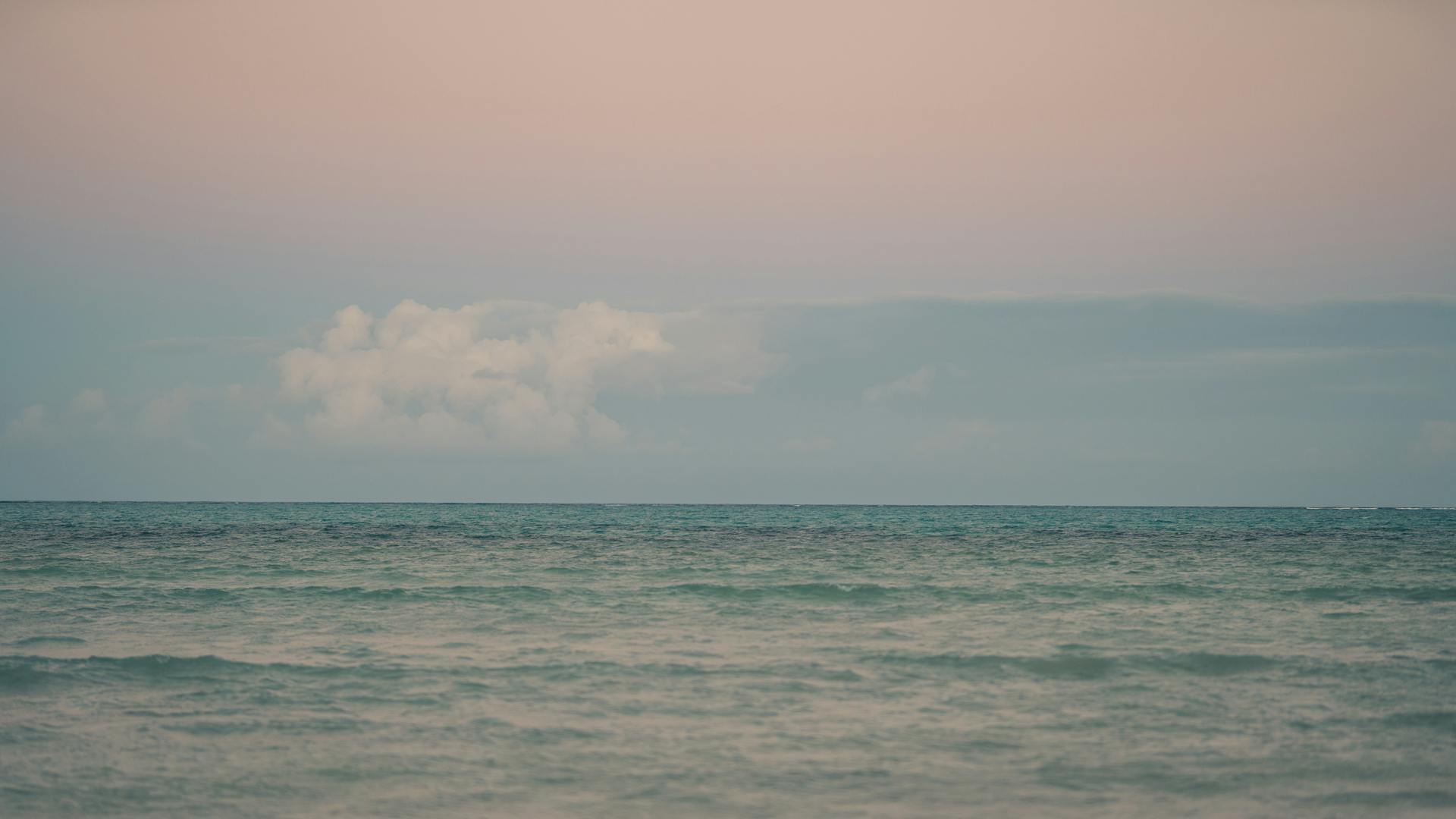 Tranquil ocean view with pastel sunset sky, perfect for travel and relaxation themes.