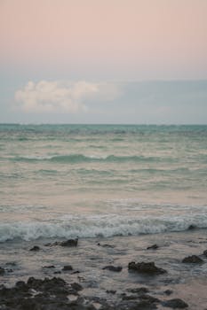 Serene beach scene at sunrise with calm waves and pastel colors, perfect for peaceful backgrounds.