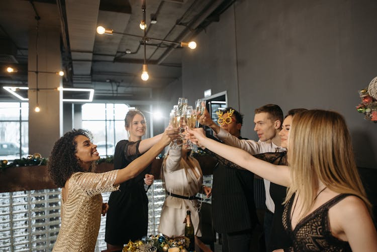 A Group Of People Toasting Gasses In A Party