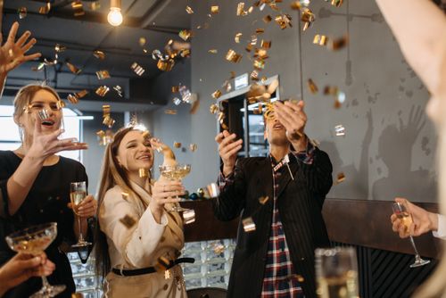 Free Group of colleagues celebrating indoors with champagne and confetti, capturing joy and togetherness. Stock Photo