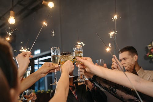 People Holding Sparklers and Glasses of Wine