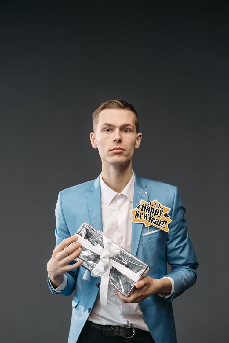 A Man In Blue Suit Holding A Gift Box