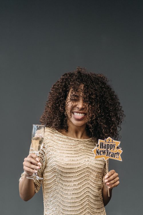Free Joyful woman celebrating New Year with champagne and festive sign. Stock Photo