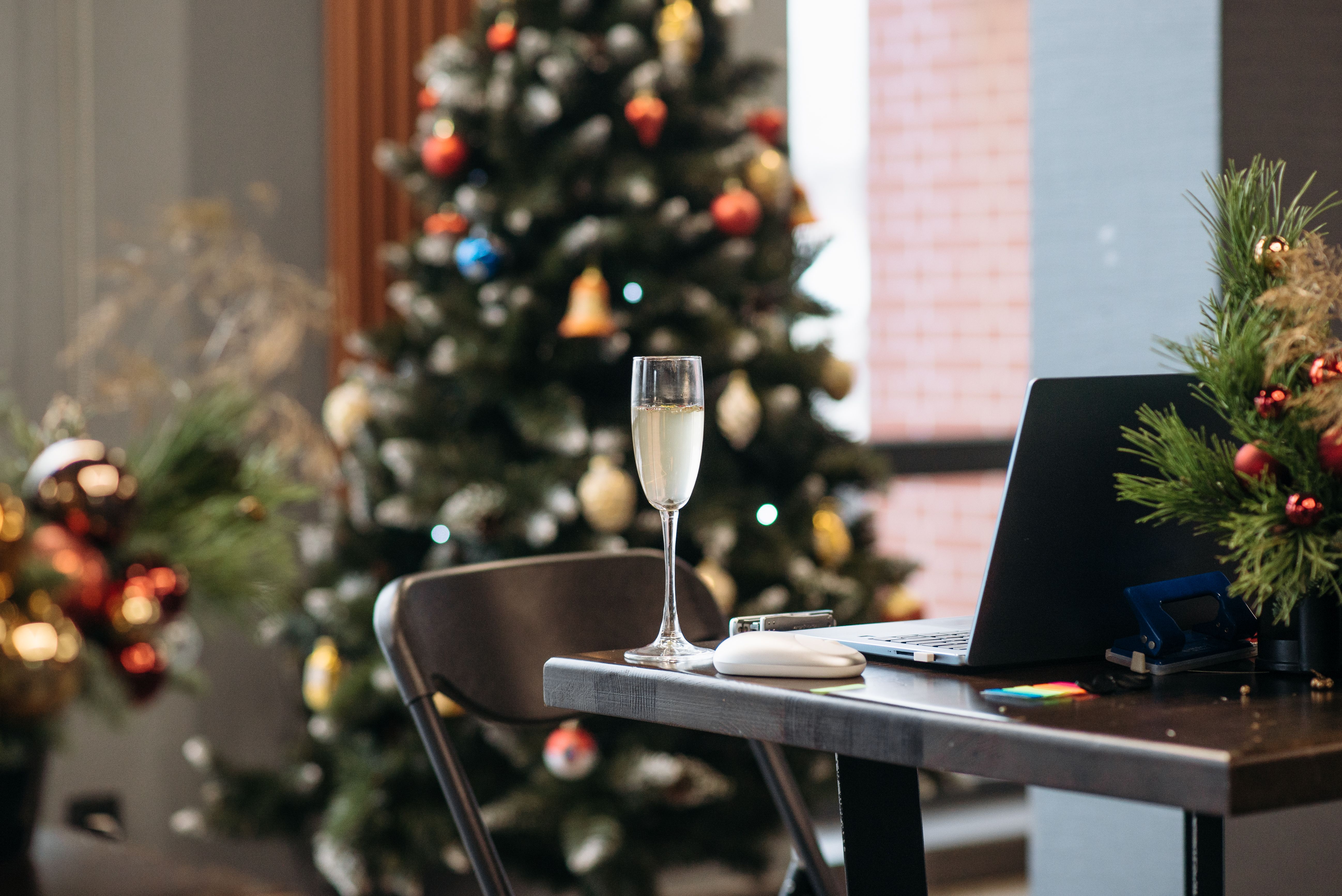 Cozy workspace with champagne, laptop, and Christmas decorations, perfect for holiday celebrations.