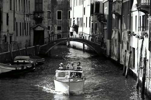 Free Grayscale Photo of People Riding a Boat on Canal in Venice, Italy Stock Photo