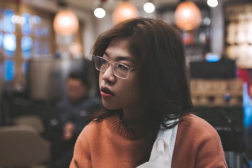 Free Profile of a woman with eyeglasses looking away in a cozy cafe environment. Stock Photo
