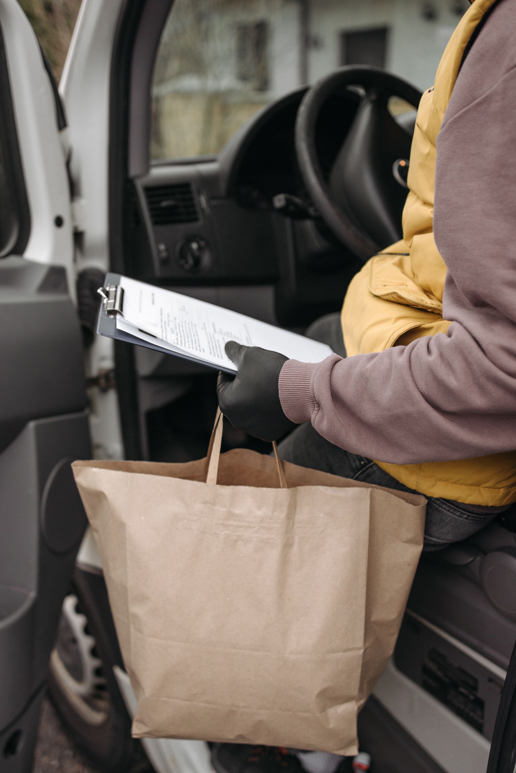 Delivery professional holding a clipboard beside a commercial vehicle
