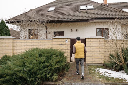A delivery person brings a package to a suburban house on a winter day.