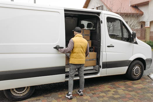 A delivery driver loads packages into a white van on a residential street.
