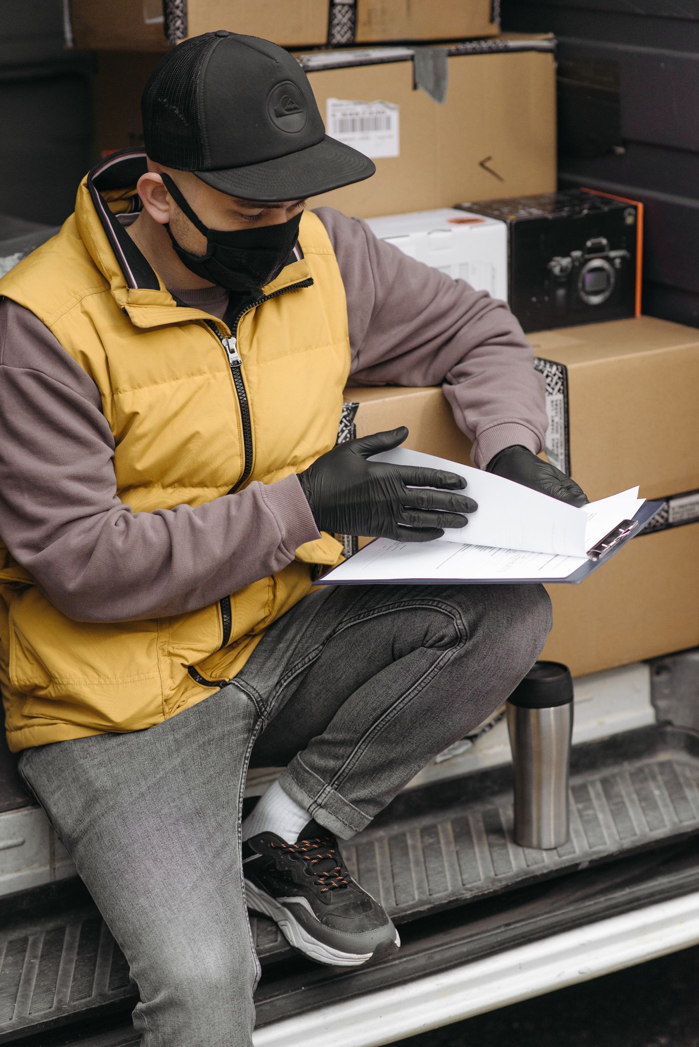 Delivery courier reviewing shipment documents beside packages in a van