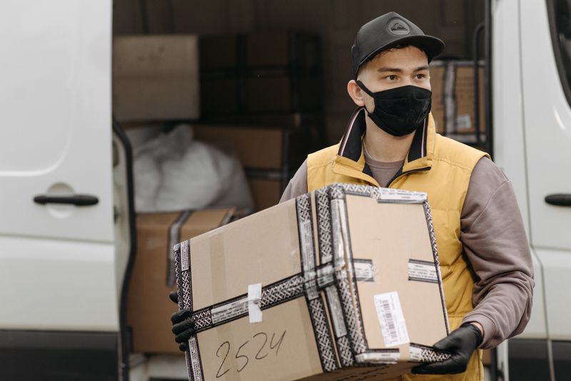 Courier lifting a cardboard box out of a delivery van