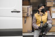 Man with Face Mask Sitting Near Brown Boxes