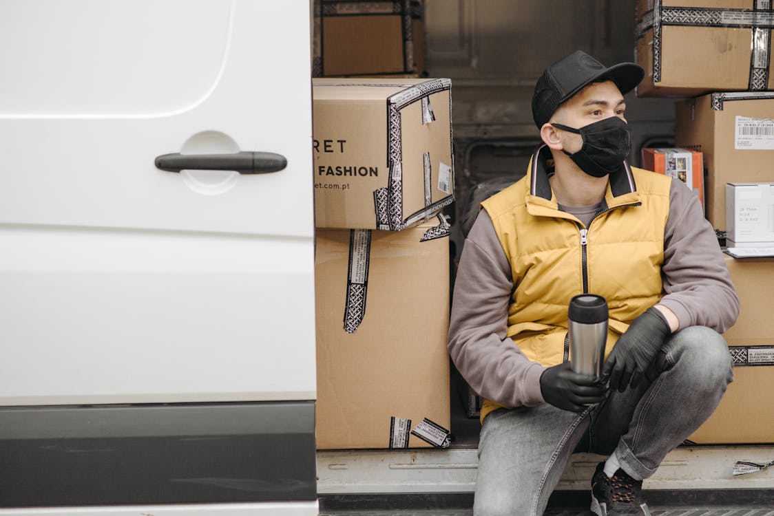 Man with Face Mask Sitting Near Brown Boxes
