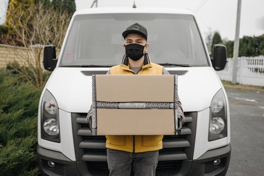 A deliveryman wearing a face mask holding a package in front of a van outdoors.