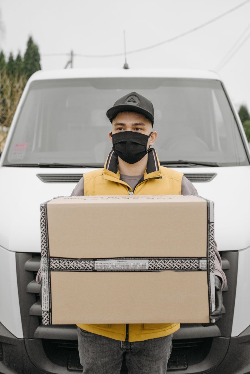 Courier holding a parcel beside a delivery van