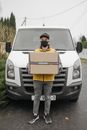 Man with a Box Standing Beside a Delivery Van