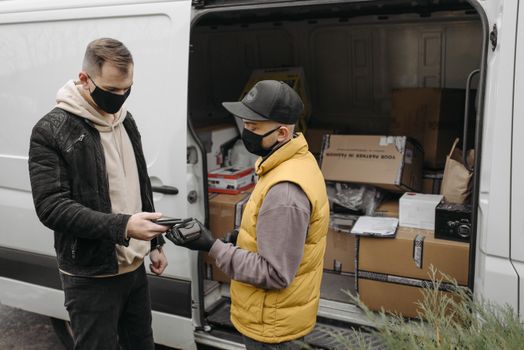 Courier handing over package to customer for contactless delivery by a van.
