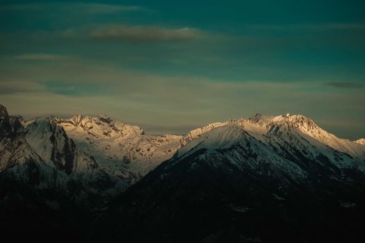 Cloudy blue sky over picturesque mountain valley covered with snow in winter evening
