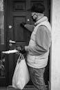 Man Holding Terminal and Bag Knocking on Door